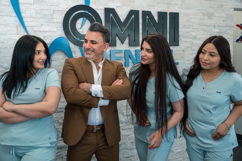Dr. Bilus Poles and the Omni Dental team in front of the office logo in Arlington Heights