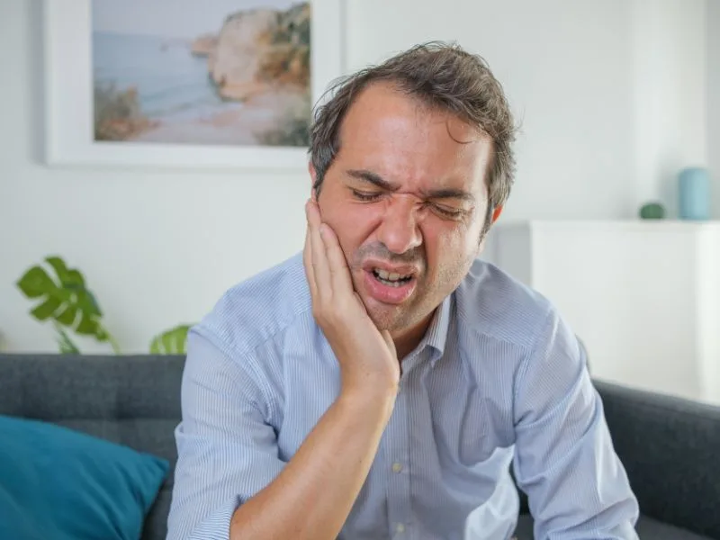 Man holding his cheek because of bruised tooth symptoms